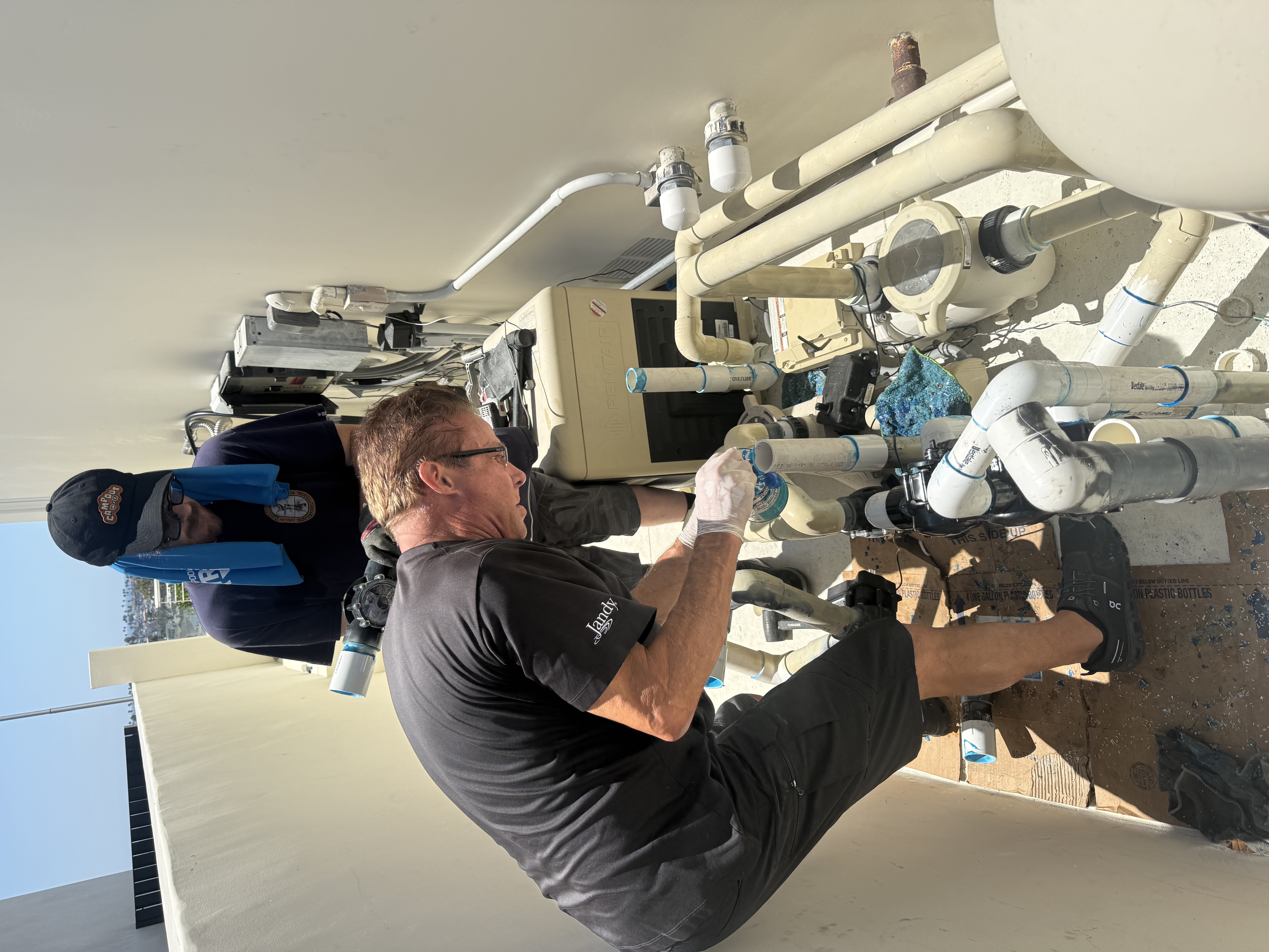 Two technicians repairing Pentair and Jandy pool equipment